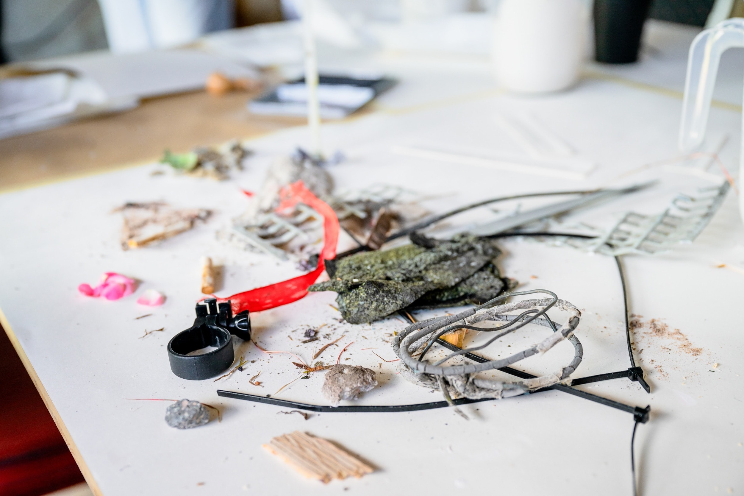 Workshop table with collected research materials, ribbons, and natural elements for design experiments